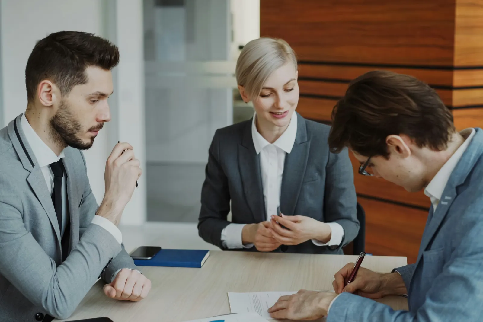 Lawyer explaining an agreement as a client signs documents at a conference table